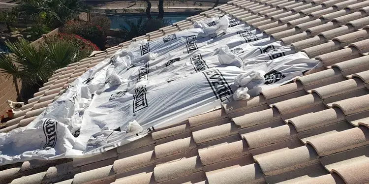 Tile roof under repair with protective sheeting
