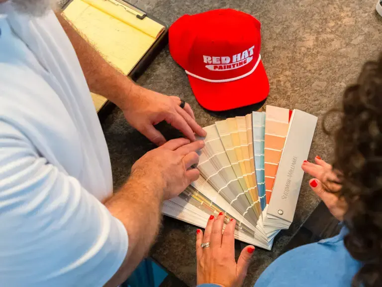 Choosing paint colors from a fan deck with a Red Hat painter