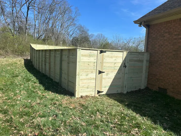Horizontal board fence with gate beside a brick house