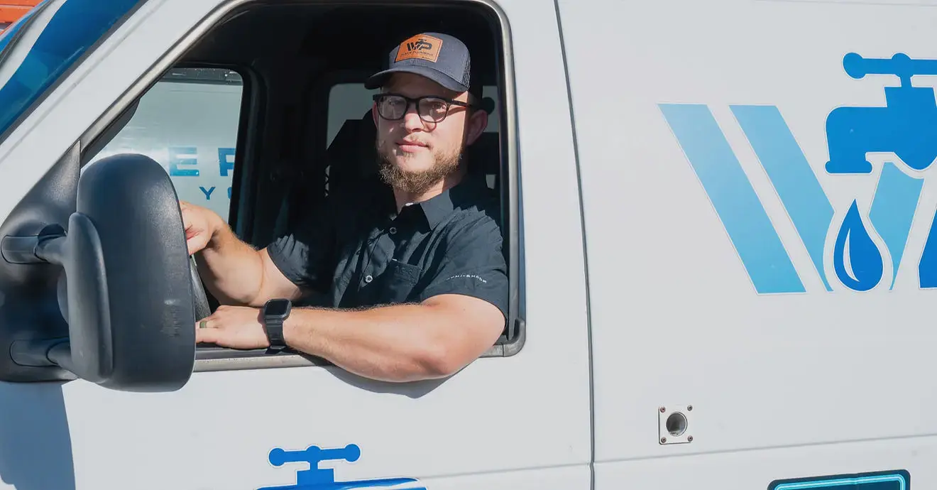 A Wave Plumbing technician at the wheel of the company van