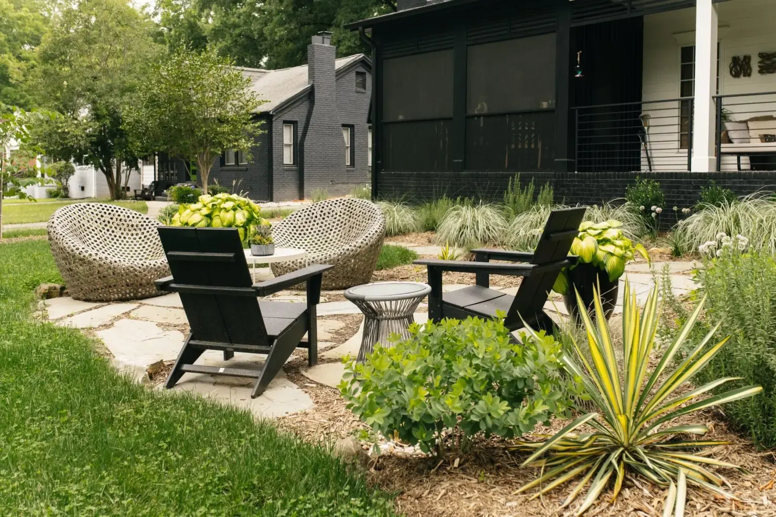 Stone patio with black chairs and ornamental grasses